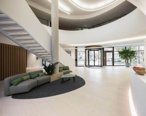 Empfangsbereich der Firma Noventi Health SE mit Lounge-Area moderner Rezeption und imposanten Treppenhaus